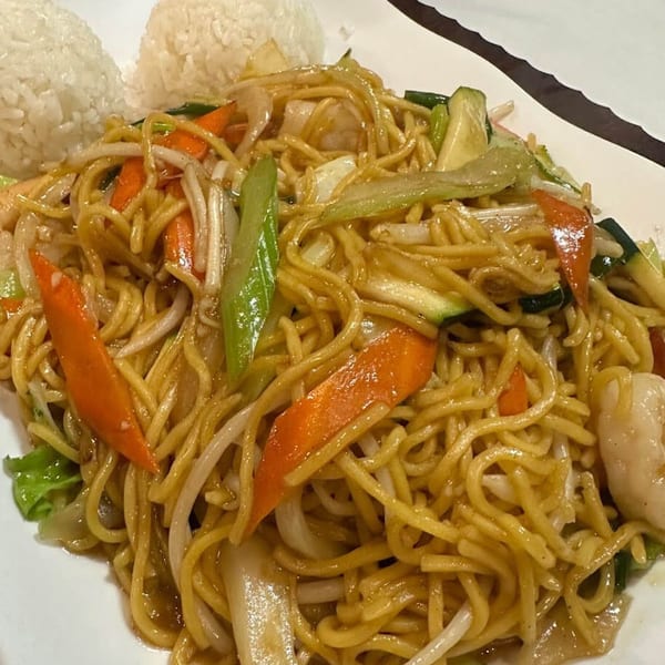 Wok-fried noodles with shrimp, carrots, zucchini, and bean sprouts, served with two scoops of white rice.